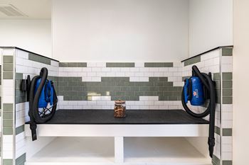 A black vacuum cleaner is on the left side of a white bench with a black mat on it.